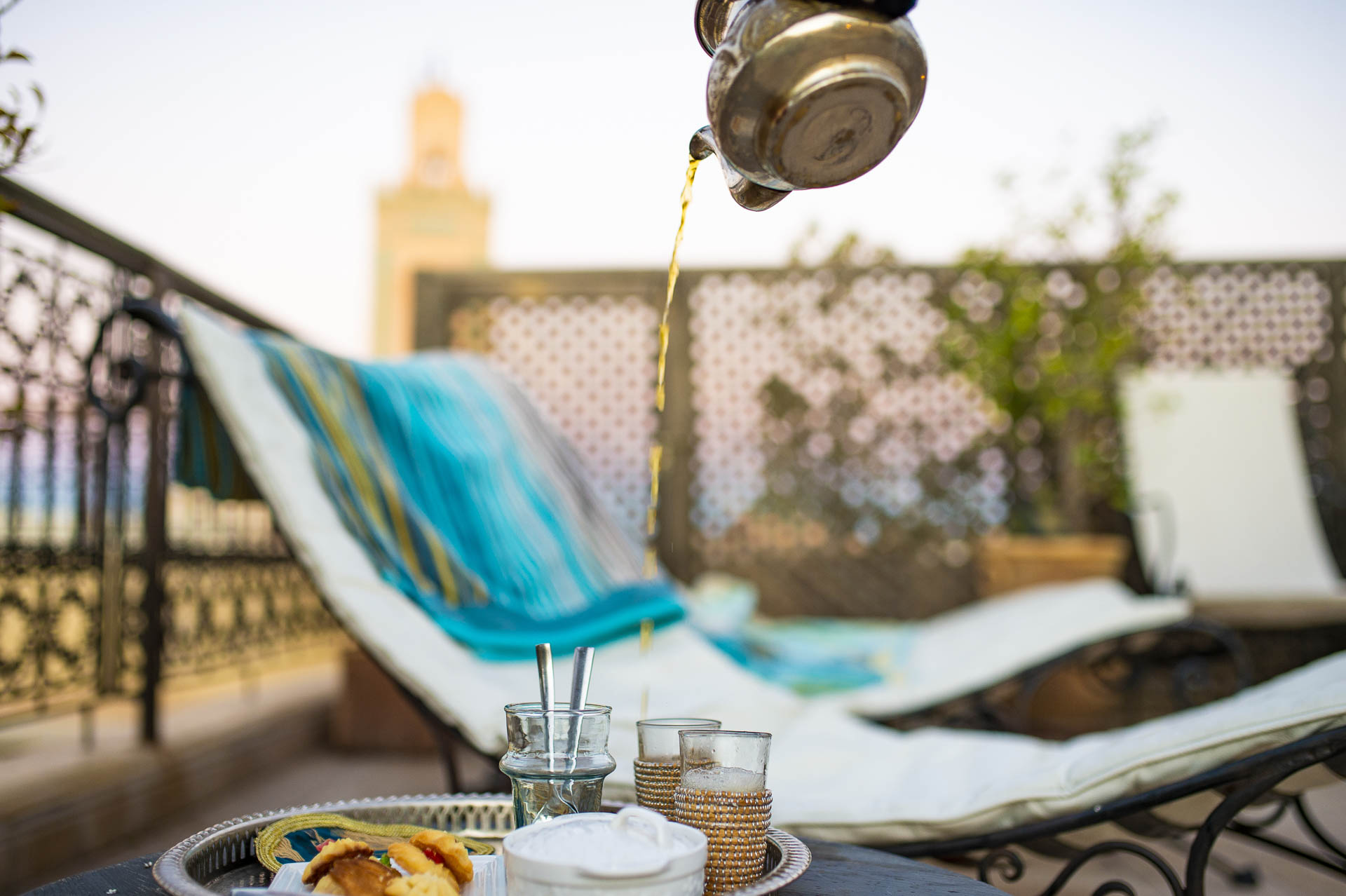 (Selective focus) Moroccan mint tea or Maghrebi mint tea is served by a teapot on the terrace of a Riad in Marrakech, Morocco. Moroccan mint tea is a green tea prepared with spearmint leaves and sugar.