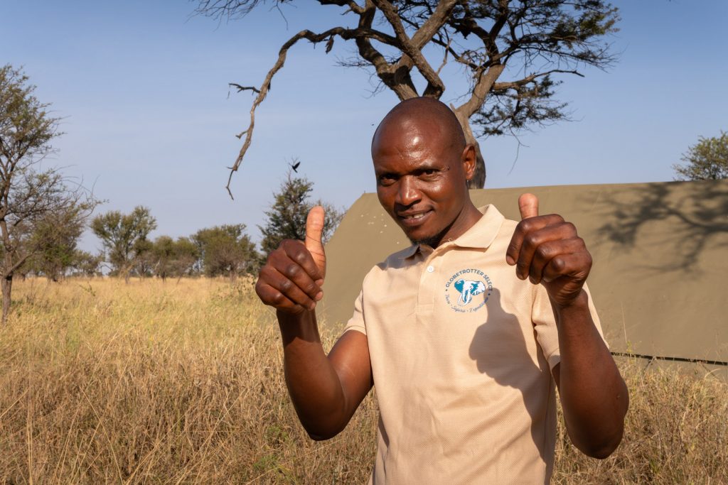 Select-Zelt-Safari Lachender Camp-Assistent zeigt Daumen hoch, Select-Zelt-Safari, Tansania, Globetrotter Select