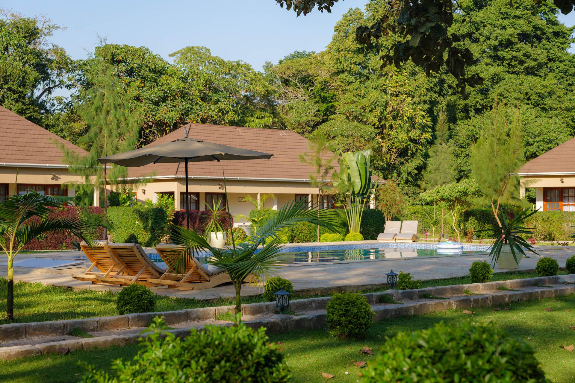 Tanzania Safari Lodge, Pool mit Liegen und Sonnenschirm mit Zimmer im Hintergrund, Tansania